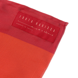 Close-up of a red silk scarf with 'Fouta Harissa' label