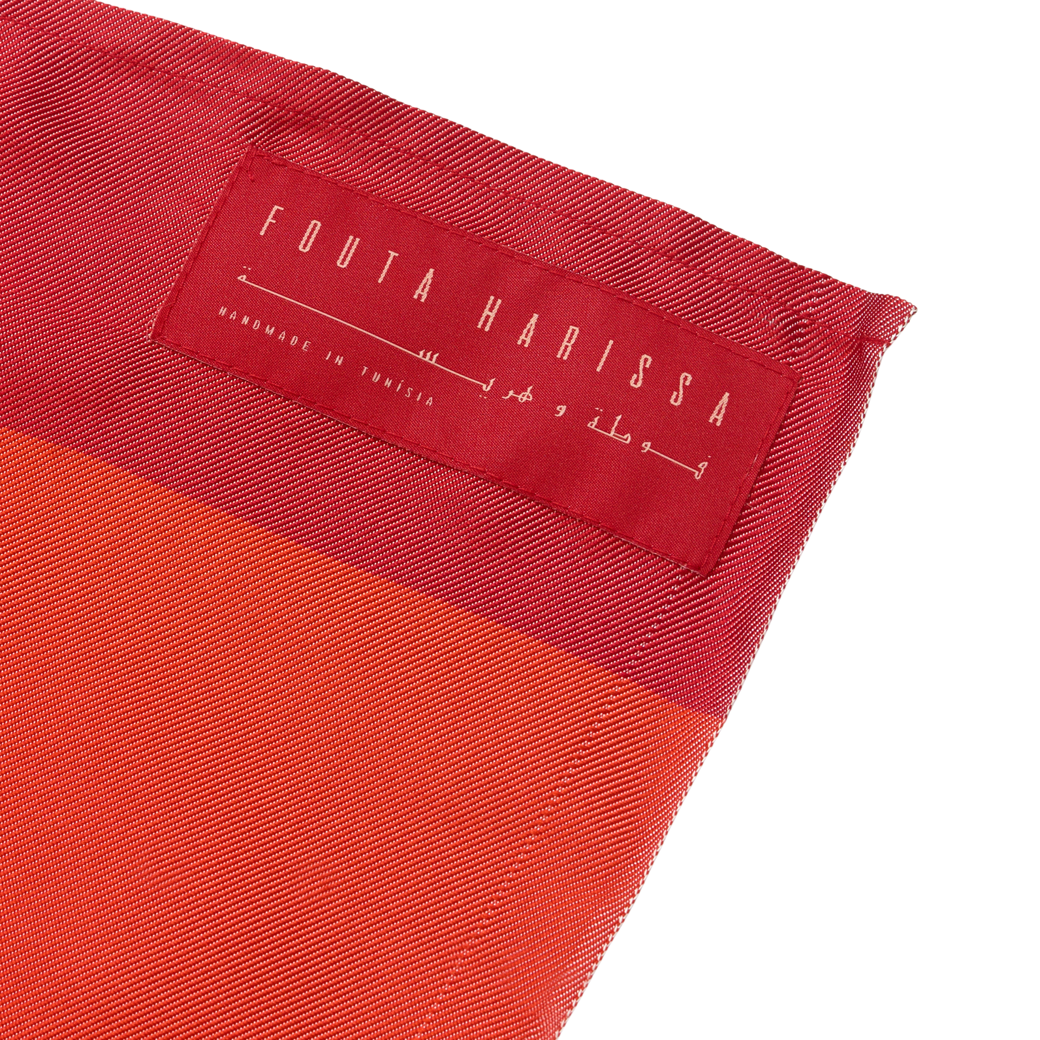 Close-up of a red silk scarf with 'Fouta Harissa' label