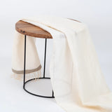 Off-white linen fouta draped over wood side table