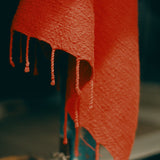 Close-up of a textured red fouta with tassels against a blurred background